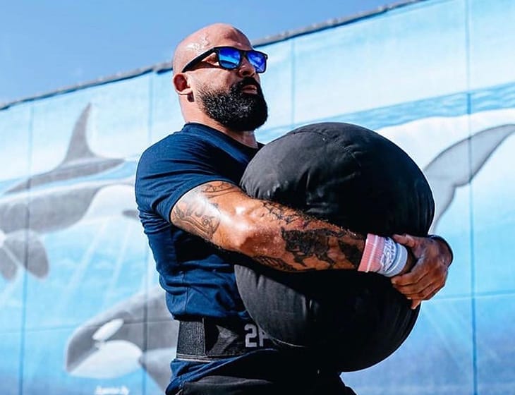 Mando Villarreal carrying a strongman sandbag outdoors